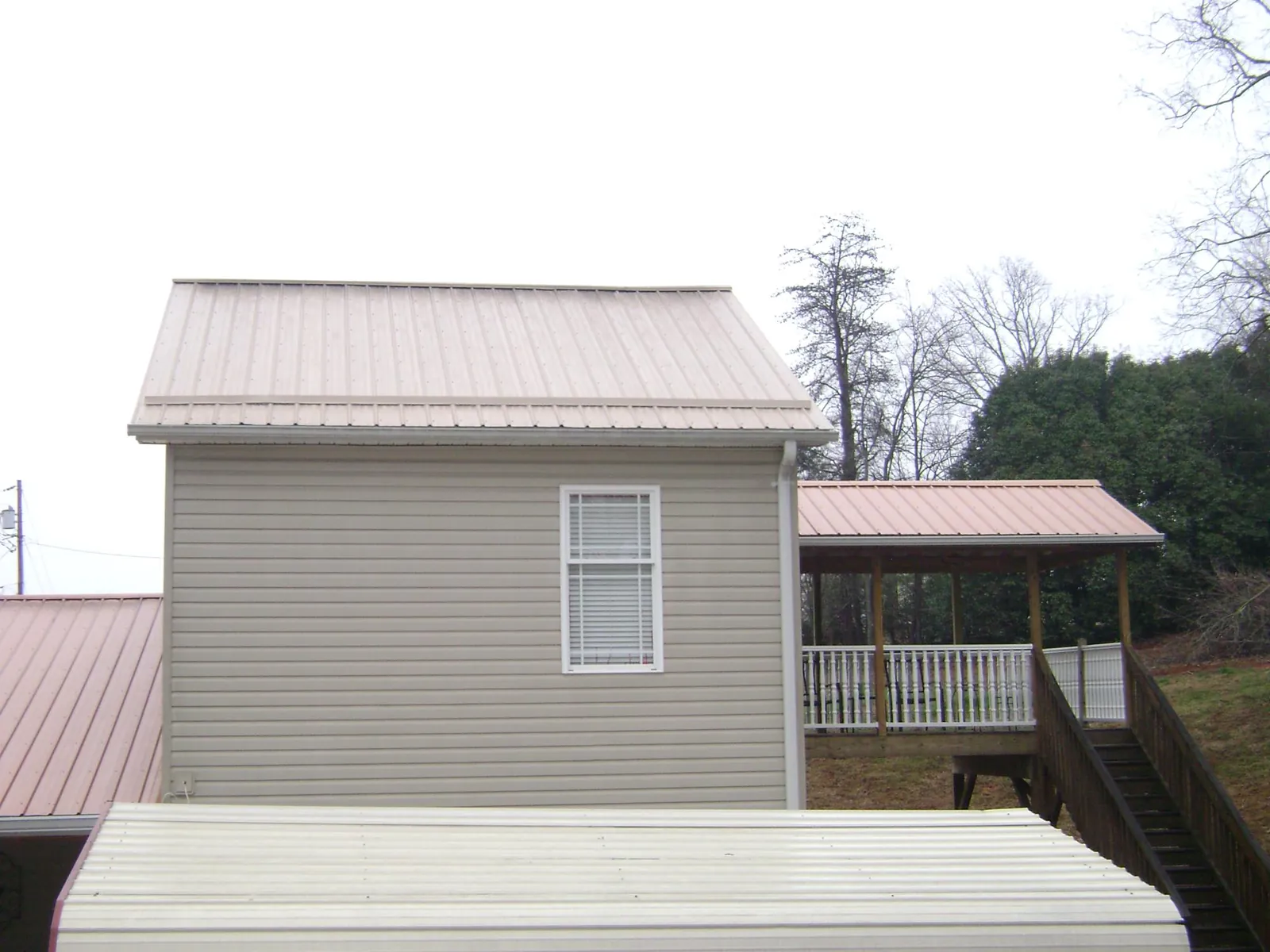 Tan metal roofs on a two story addition and attached porch, from a Roof Replacement job in Sisseton