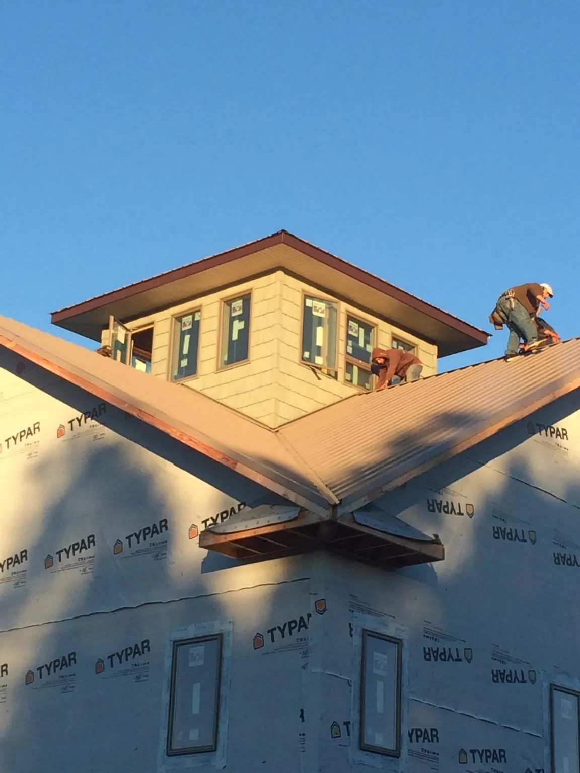 Roofers working around a rooftop cupola on a new metal roof at sunset — Roof Waterproofing in Sisseton by Roofing Brothers